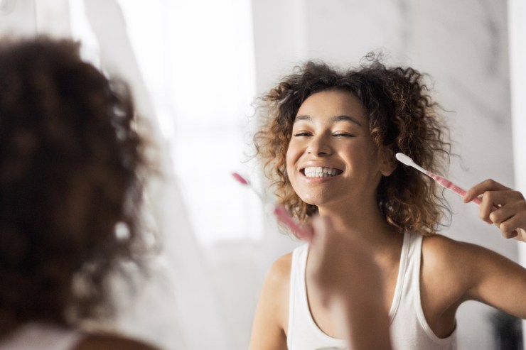 Ragazza che si guarda i denti allo specchio