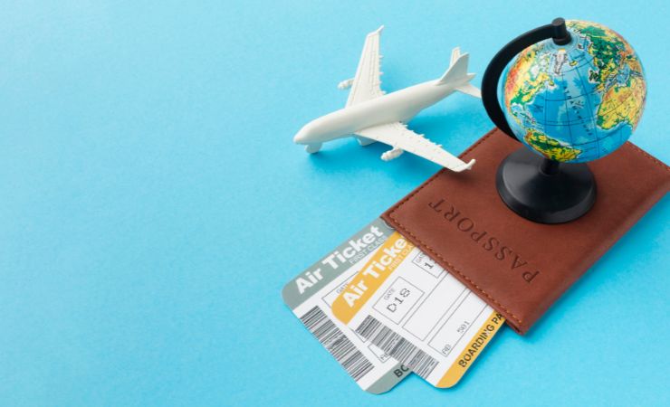 passaporto, mappamondo e aereo in miniatura su sfondo azzurro