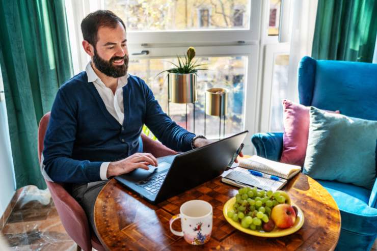 Uomo che lavora con il pc da casa sul tavolo della cucina