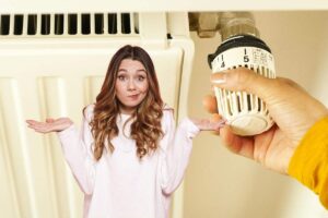 donna dubbiosa e mano che regola termosifone