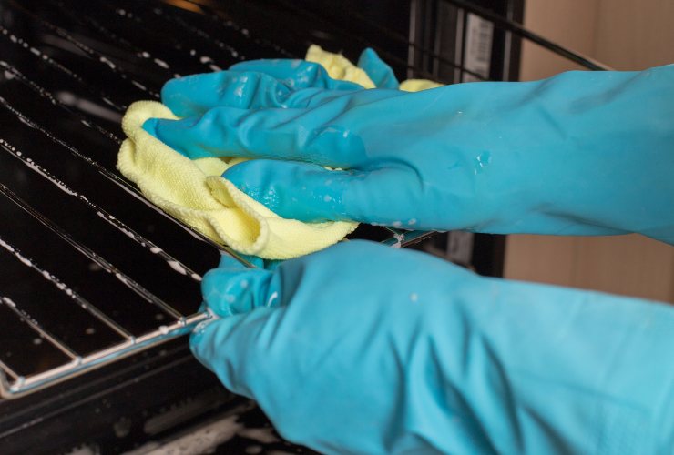 mani che puliscono il forno