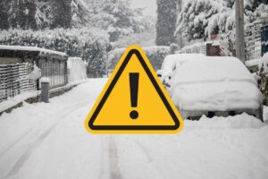 strada innevata e segnale di pericolo